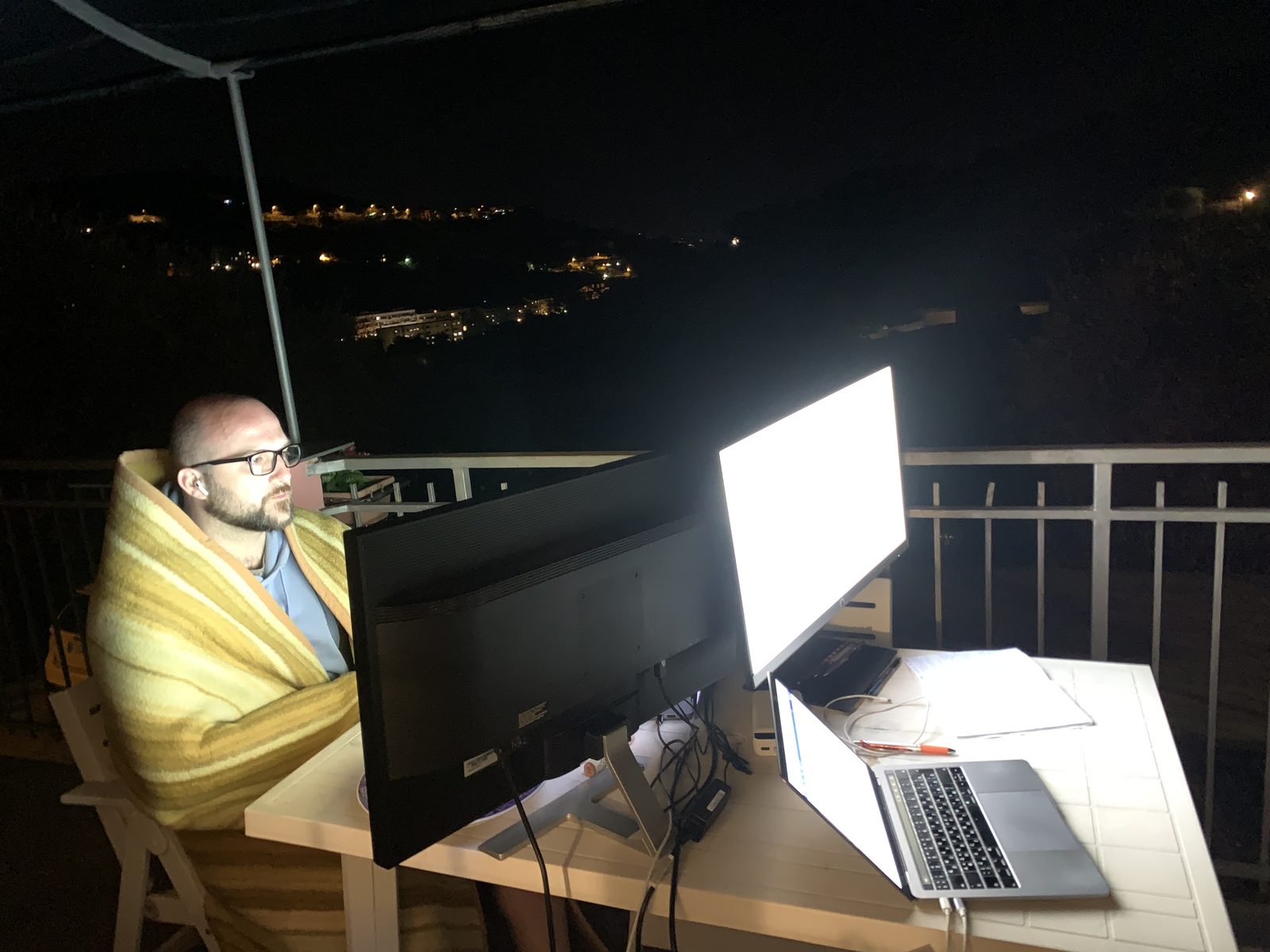 Working late at night on a balcony, wrapped in a blanket