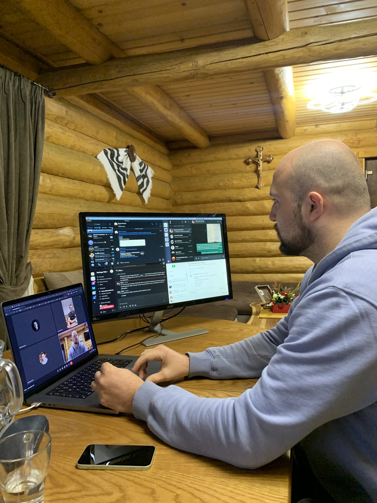 Dimitry working at two screens in a log cabin
