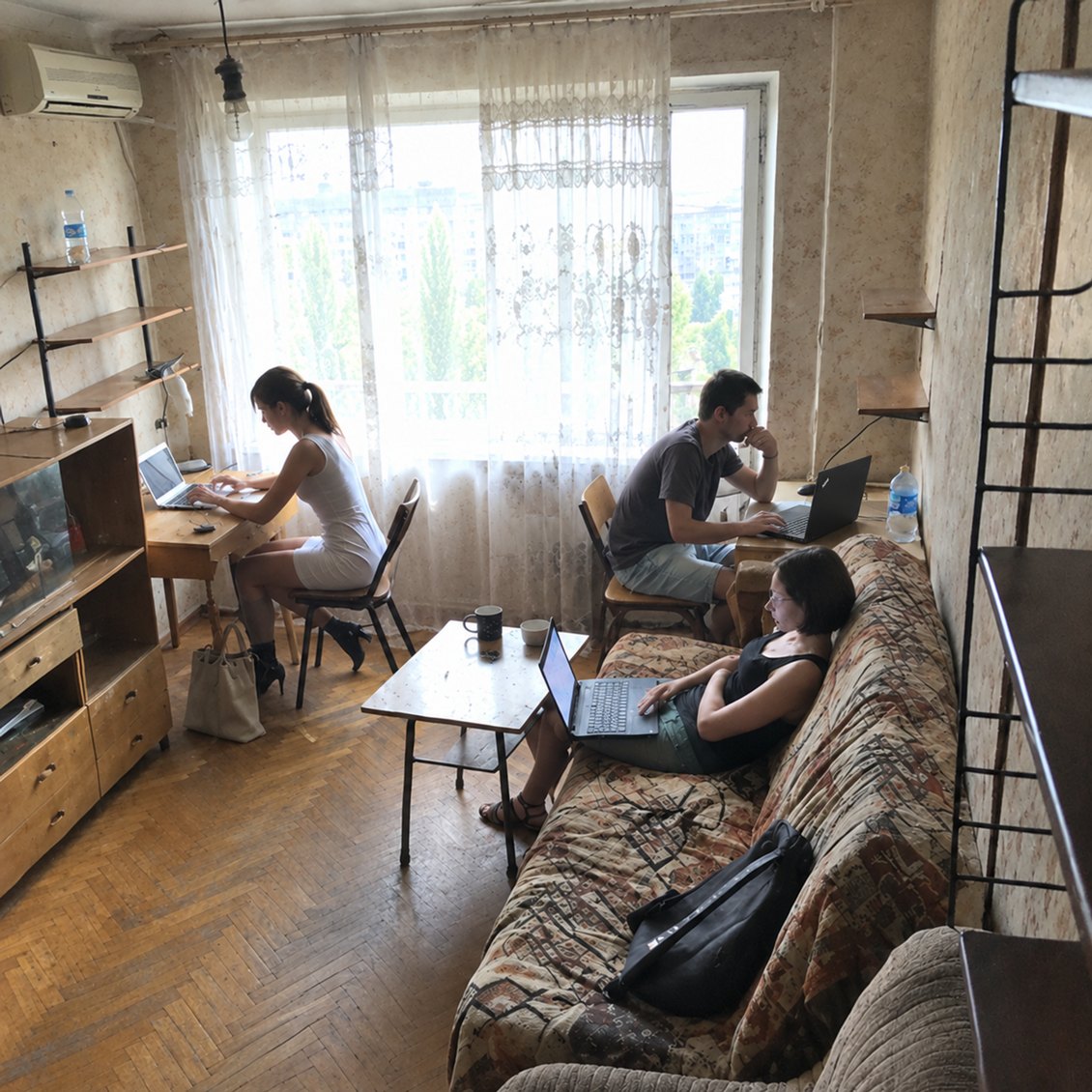 The first DDGO office: three people working on laptops in a Soviet-era apartment
